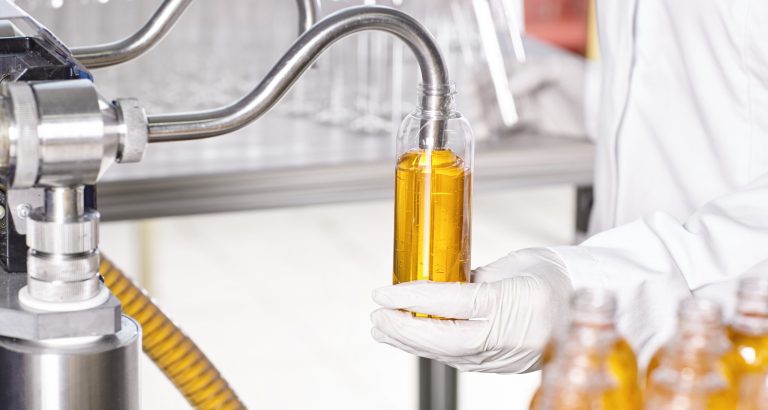 Large scale production of cosmetic in factory.Chain of production of new kind of cream by researcher. Interior of modern laboratory. A researcher in white medical gown holding glassware in hands